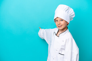 Little chef boy isolated on blue background extending hands to the side for inviting to come