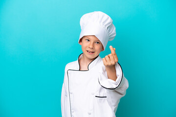 Little chef boy isolated on blue background making money gesture