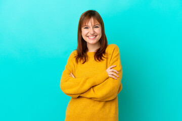 Obraz premium Redhead girl isolated on blue background keeping the arms crossed in frontal position