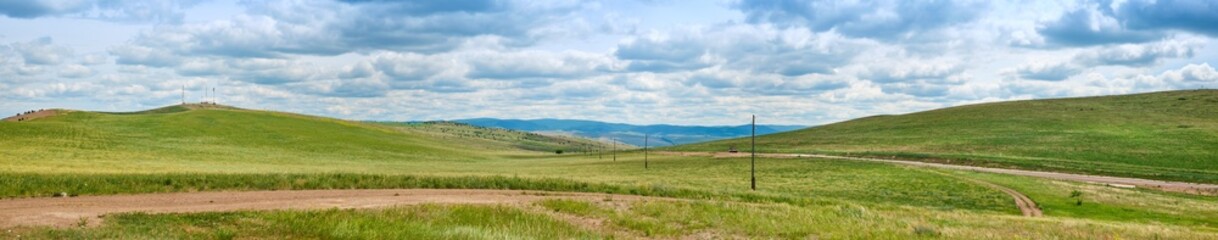 Bald Mountain in the Buryat Republic of Russia. Green hills against a blue sky with clouds.