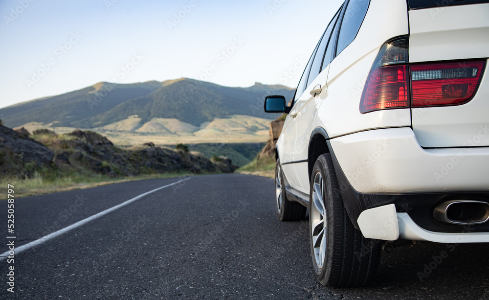 Wall mural white car moves on the road among the mountains