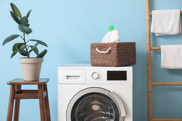 Washing machine with basket and detergent near blue wall in laundry room