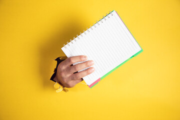  notepad in hand on yellow background.