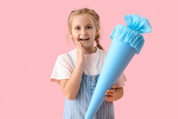 Surprised little girl with blue school cone on pink background