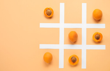 Tic tac toe game with ripe apricots and paper grid on color background