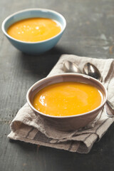 Pumpkin soup in a bowls on a wooden surface