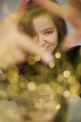 A pretty woman in festive lights and flares holding up her hands a a photo frame