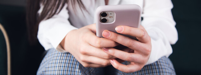 Woman hand holding mobile phone and sitting on sofa