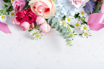 Flowers with roses and pink ribbon on marble background