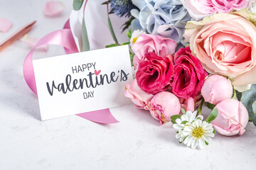 Happy valentine day card on flower bouquet with roses on marble table