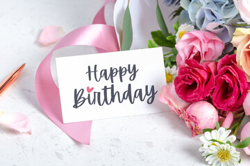 Happy birthday card on flower bouquet with roses and pink ribbon