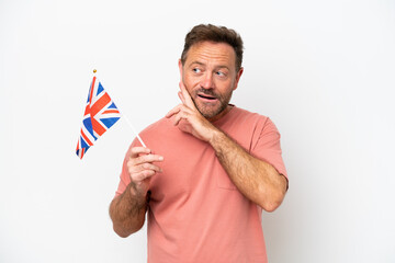 Middle age caucasian man holding English flag isolated on white background looking up while smiling