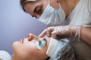 The master removes the composition for lamination from the client's eyelashes with a cotton swab. Eyelash perm procedure.