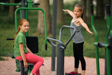 Fototapeta na wymiar Two teenage girl friends on outdoor fitness equipment.
