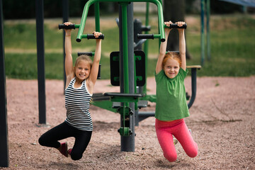 Fototapeta na wymiar Teenage girl's girlfriends on outdoor fitness equipment.