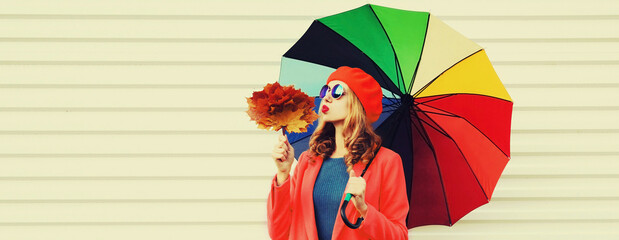 Autumn portrait of happy cheerful young woman with colorful umbrella and yellow maple leaves...
