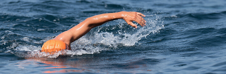Man swimmer swimming crawl in blue sea, training for triathlon