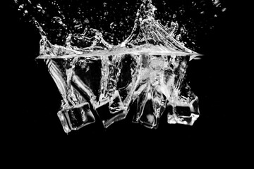 Black and white image of ice cubes in water with bubbles on a black background.