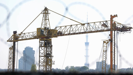 Yellow construction crane on the background of the city. Camera focusing on the object.