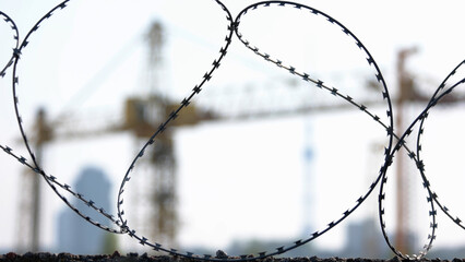 Close-up barbed wire and yellow crane on the background. Camera focusing on the object.