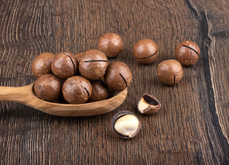 Macadamia nuts and nut shells on a wooden background.