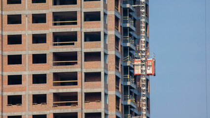 Building under construction with an elevator lift. Workers moving down with an elevator.