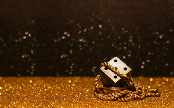 dice and gold chain conceptional pic taken in black and gold background to show lifestyle of gambling and richest