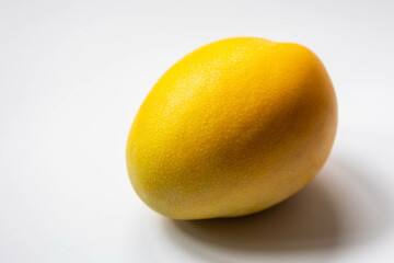 Selective focus of fresh ripe yellow fruit on white background, A mango is an edible stone fruit...