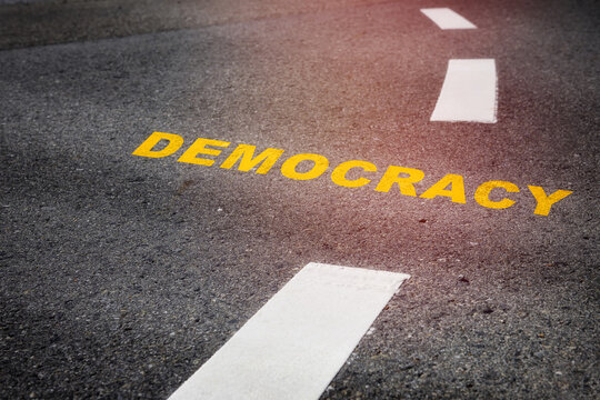 Democracy written on asphalt road. Future ahead concept and freedom idea