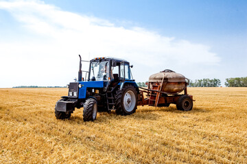 Tractor working in wheat field. Agriculture background. Harvest season