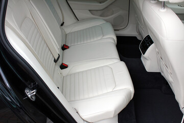 White leather interior of the luxury modern car. Leather comfortable white passenger seats and armrest. Modern car interior details. Rear passenger seats. Right view.