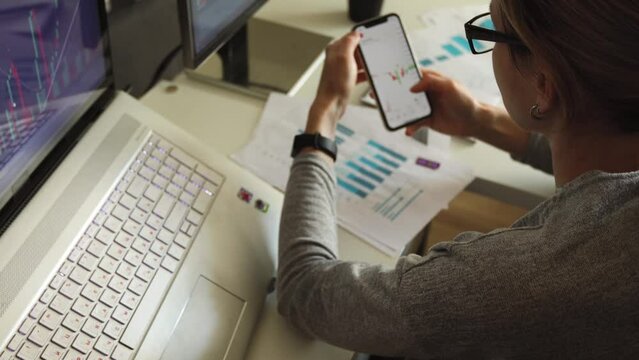 A young woman trades on the stock exchange through a smartphone. Private investor