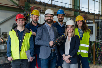 Young man worker with Down syndrome with manager and other collegues working in industrial factory, social integration concept.