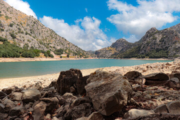 gor blau reservoir with large water capacity located between the mountains of mallorca with a cloudy sky.