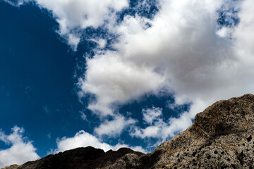 large isolated clouds in a blue sky and mountain