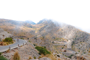 road in mallorca with the name of knot of tie, road in the middle of the mountains 
 with a cyclist going up from sa calobra or cala tuent