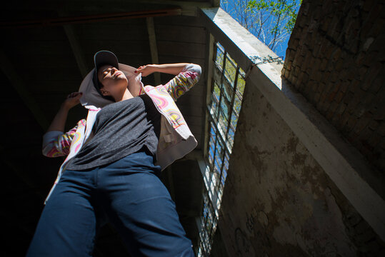 Young female hip hop dancer dancing and jumping in abandoned building on a sunny summer day
