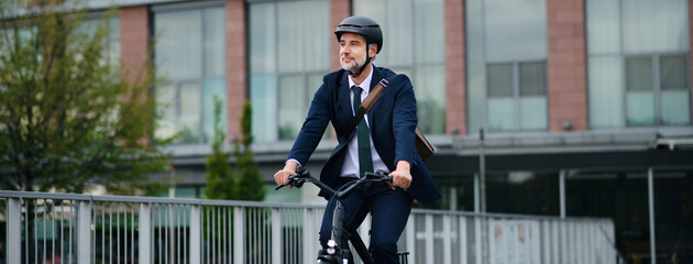 Businessman commuter on the way to work, riding bike in city, sustainable lifestyle concept. Wide photography.