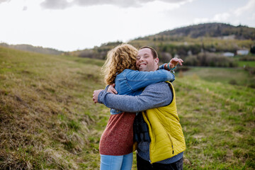 Outdoor portrait of mother hugging her grown up son with Down syndrome, motherhood concept.