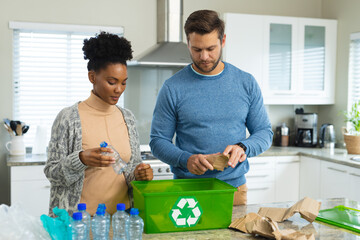 Image of happy diverse couple recycling plastic bottles