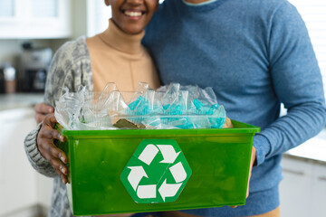 Image of midsection of diverse couple recycling plastic bottles