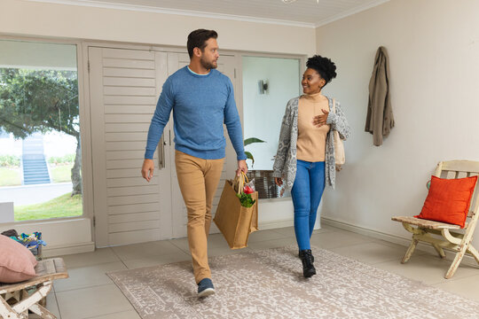 Image of happy diverse couple returning home with shopping