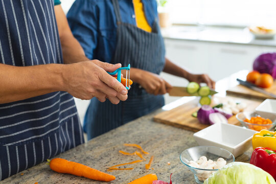 Image of hands of diverse couple cutting vegetables and preparing meal together