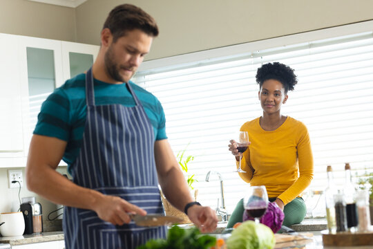 Image of diverse couple preparing meal together in kitchen