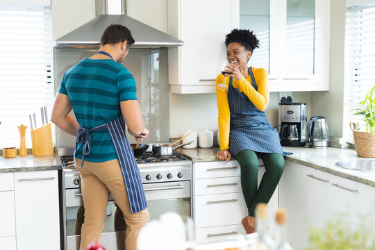 Image of happy diverse couple preparing meal together in kitchen