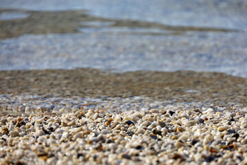 Small pebble stones on sea beach with transparent water. Natural background for summer vacation