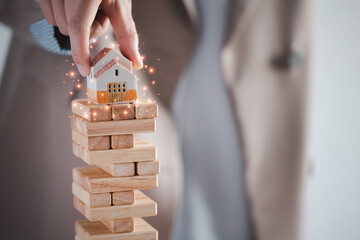 woman's hand holding home model on top of wood block stack