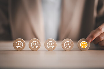 closeup businesswoman hand picking happy emotion face on wooden piece arranged on table for...