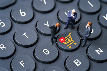 Businessmen miniature figure standing on computer keyboard with shopping trolley cart and...