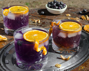 Refreshing purple drink with blueberries ice and orange slice. Drink concept